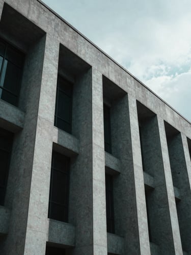 Low-angle architectural photography of a modern courthouse facade with sharp geometric concrete lines, dramatic high-contrast shadows, cool overcast daylight, projecting absolute legal authority, 35mm