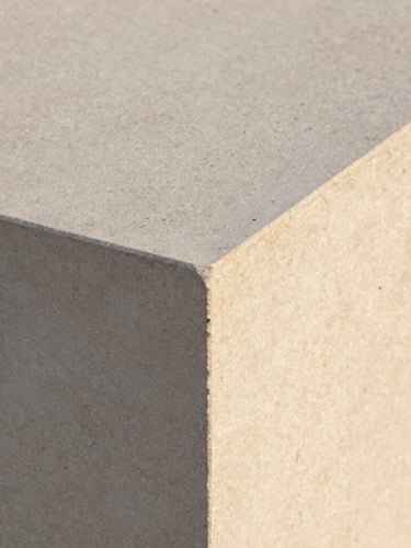 Extreme close-up of raw travertine stone texture alongside a smooth concrete edge, warm morning light, architectural detail, crisp focus