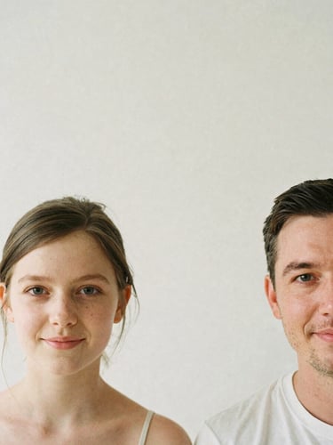 Minimalist close-up portrait of Patrick and Lea smiling softly, warm neutral background, soft diffused overcast daylight, 35mm film