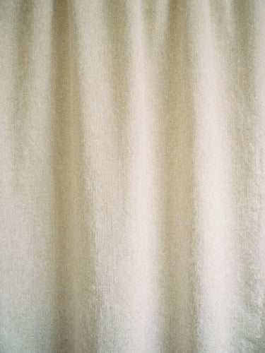 Minimalist close-up of soft beige linen texture, warm overcast daylight, gentle shadows, elegant Japandi aesthetic, 35mm film