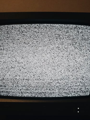 Extreme close-up of a vintage CRT monitor displaying static noise, high contrast black and white, moody cinematic lighting, 35mm grain, anamorphic frame