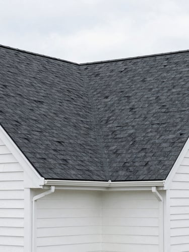 Wide-angle exterior shot of a Syracuse home with a newly installed dark shingle roof and clean siding, sharp construction photography, bright overcast daylight.