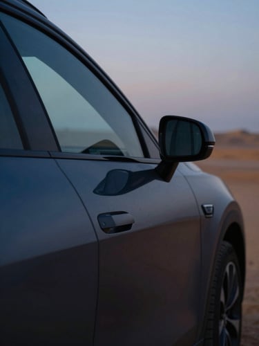 Moody close-up of a premium modern vehicle reflecting sharp twilight desert light, deep charcoal tones, 35mm