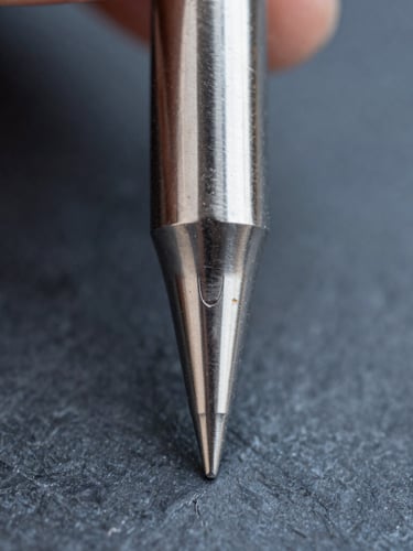 Extreme macro photography of a pristine silver-plated soldering tip point, sharp metallic reflections, cool slate background with subtle copper highlights, 3:4 portrait