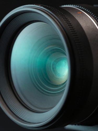 Extreme close-up of an anamorphic camera lens reflecting a sharp neon cyan light, matte charcoal housing, high-contrast shadows