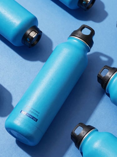 Dynamic angle shot of premium anodized water bottles with bright cyan branding, crisp studio lighting, deep blue shadows