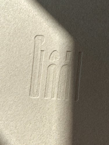 A macro detail of heavy cotton paper with deep letterpress ink impressions, sharp directional light, dramatic shadows, desaturated warm tones.
