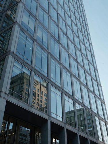 A low-angle exterior shot of a modern architectural office building in Toronto, featuring clean glass panels reflecting crisp daylight and a cool blue sky.