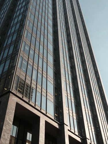 Low-angle architectural shot of a modern glass skyscraper in Houston, sharp shadows, dramatic afternoon sun cutting through steel structures, high-contrast.