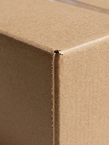 Prism-like studio lighting reflecting off a high-end rigid paperboard box corner, revealing absolute alignment and clean seams, architectural framing