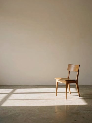 Warm minimalist medium-format photograph of a quiet, sunlit architectural photography studio in Los Angeles, soft natural light casting long elegant shadows across a concrete floor, a single wooden chair placed in generous negative space, 50mm lens, warm tan tones.