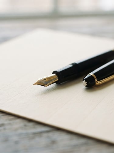 Close-up of a fountain pen resting on a crisp, heavy-weight legal document, soft diffused daylight, warm paper texture, shallow depth of field, 35mm