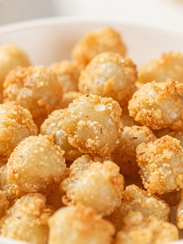 Close-up macro shot of crispy, golden-brown air-fried Soya Crunch scattered over a steaming bowl of noodles, shallow depth of field, natural light