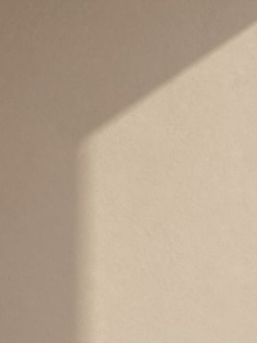 Minimalist abstract photography of warm plaster texture with soft architectural shadows, sand and neutral tones, diffused natural light, clean balanced composition, 35mm