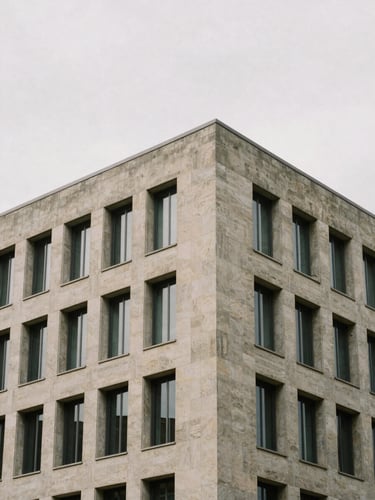 Architectural corner of a modern stone and concrete office building, soft overcast daylight, desaturated earth tones, clean geometric lines