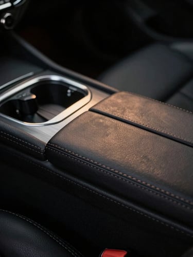 Low-key dramatic close-up of pristine hand-stitched black leather car interior, soft golden hour light reflecting off brushed metallic accents, 35mm anamorphic.