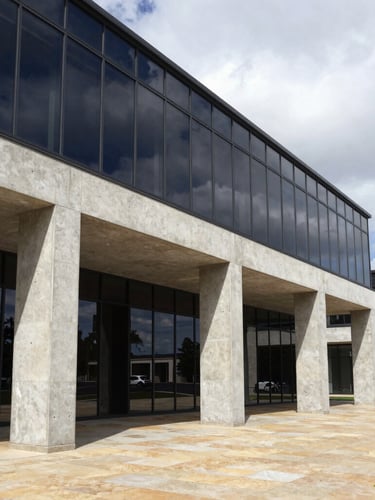 Sharp architectural environmental shot of a modern concrete and glass commercial structure with high-contrast geometric shadows, bright overcast daylight, 35mm photography