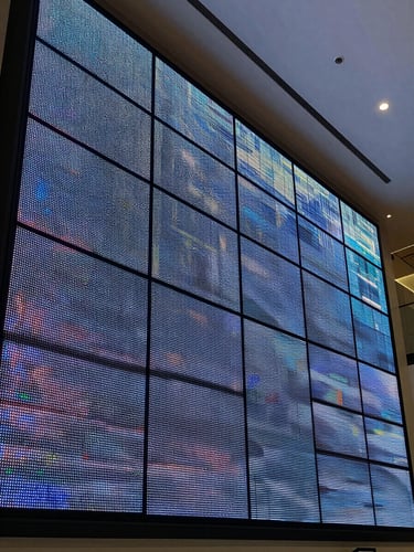 Close overhead architectural shot of a large-format LED videowall installed in a corporate lobby — panels perfectly aligned, cool studio lighting from above, individual pixel modules visible at the seams, no people, operational and powered on displaying abstract data