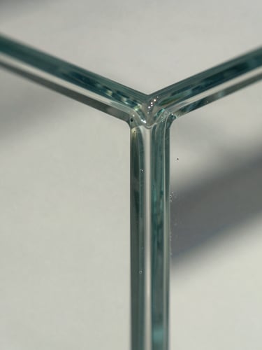 Macro close-up of a perfectly clean, sharp glass corner reflecting bright natural daylight, showing extreme cleanliness and detail.