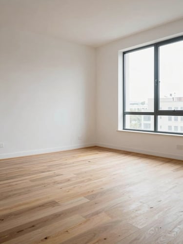 Wide-angle corner view of an empty modern apartment interior, daylight from tall windows casting soft even light across pale hardwood floors and white walls, architectural and still