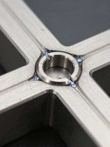 Macro shot of precise laser-welded joint on brushed AISI 304 stainless steel, cold metallic lighting, high contrast, industrial product photography, 50mm