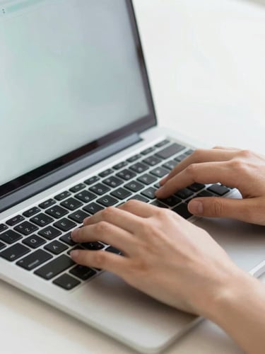 Close-up of hands typing on a laptop keyboard, clean bright digital workspace, soft daylight, sharp focus on modern interface