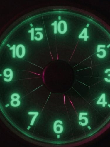 Close-up of vintage analog radio dial glowing with neon green numbers, cracked glass, dark background, heavy film grain