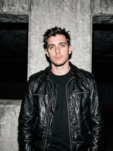 Candid portrait of a London creator with a heavy leather jacket standing in front of brutalist concrete, harsh direct flash, gritty 35mm film grain, high contrast.