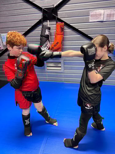 Boxe éducative : une jeune fille enchaîne des coups de poing face à un garçon en garde