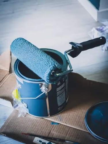 Blue painting roller on top of paint can