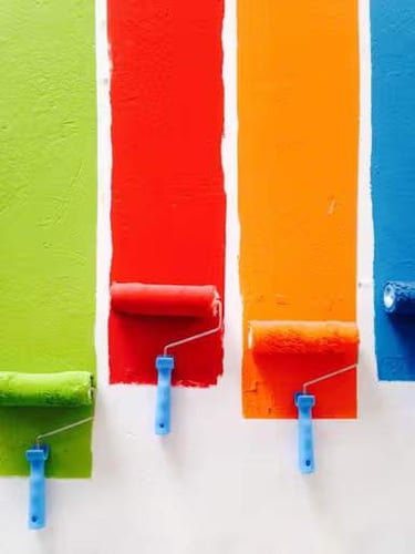 Paint rollers of bright color rolling paint on a wall