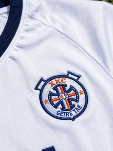 Close-up of a vintage football shirt collar, detailed embroidery of a classic crest, soft daylight, sharp focus on fabric textures, 50mm lens
