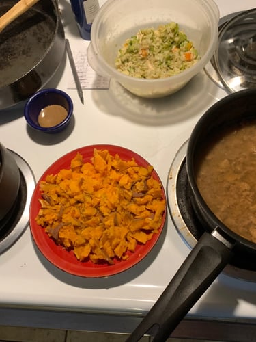 A variety of healthy home-cooked dishes including black beans, sweet potatoes, and vegetable rice on a white stove.