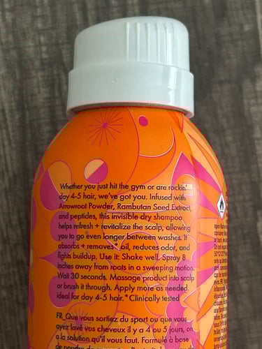 orange and pink Amika Perk Up Plus Dry Shampoo bottles on a bathroom counter