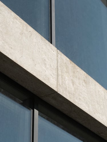 Macro architectural close-up of sharp concrete angles and glass under cool natural daylight, high-contrast slate shadows, 35mm