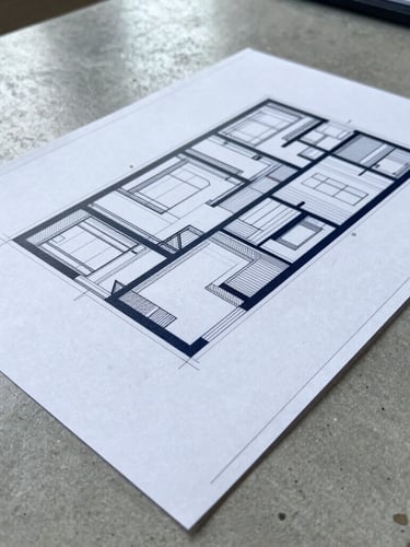 Close-up of a structural blueprint sheet resting on a polished concrete desk, cool daylight, high-contrast details