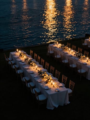 High-angle cinematic drone perspective of a luxury outdoor reception at twilight, golden lights reflecting on water.