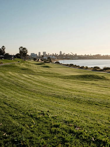 Sun-drenched wide panoramic landscape of San Diego Hills memorial park, manicured green lawns, serene lake in the distance, soft morning light