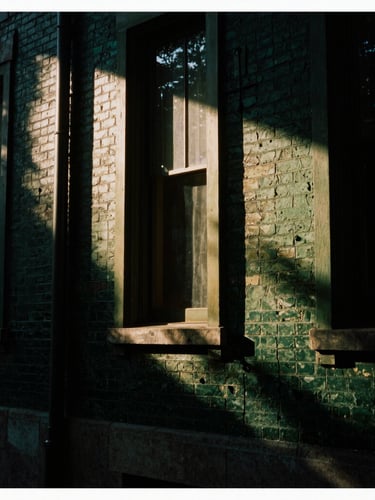 Moody editorial photography, tight architectural crop of a historic Georgetown brick facade with deep shadows, low-key side-lighting, 35mm film style