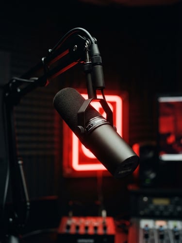 Moody close-up of a professional broadcast microphone in a dark studio, dramatic red neon backlight, high-contrast shadows, 35mm photography