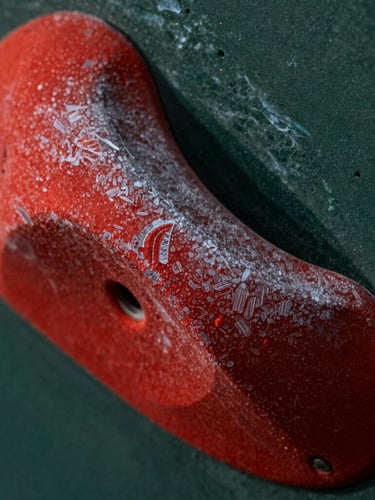 Macro shot of raw crimson polyurethane climbing holds, dramatic side-lighting highlighting the high-friction tactile texture and dual-texture boundary, 35mm