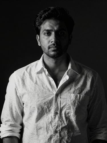 High-contrast black and white portrait of director Nishad Raj Rana on a dark film set, soft directional key light, deep shadows, cinematic anamorphic framing