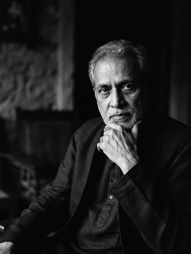 High-contrast black and white cinematic portrait of Narendra Jetley, moody low-key lighting, deep shadows, soft directional key light, anamorphic widescreen format