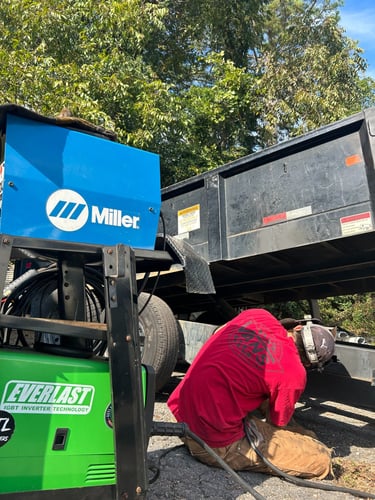 a ma repairing a trailer with a everlast welder next to him