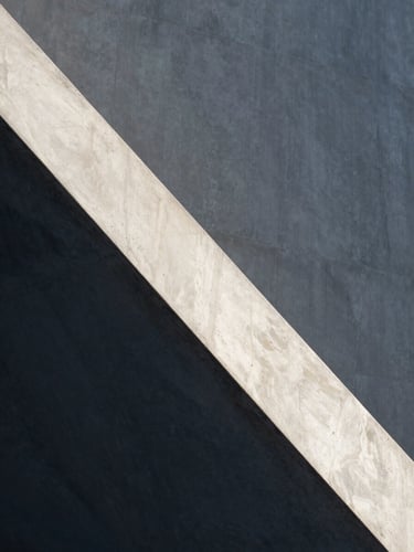 Minimalist concrete and marble architectural detail with sharp diagonal shadows and soft natural daylight, clean lines, elegant atmosphere