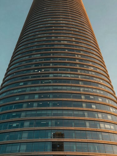 Low-angle heroic architectural shot of Port Baku Towers facade during golden hour, glass reflecting warm light, sharp detail, 35mm