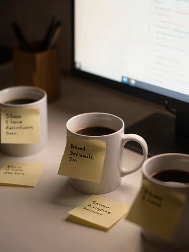 cozy lo-fi photography, warm monitor glow, close-up of a messy desk with three coffee mugs, handwritten sticky notes with code corrections, shallow depth of field, 35mm