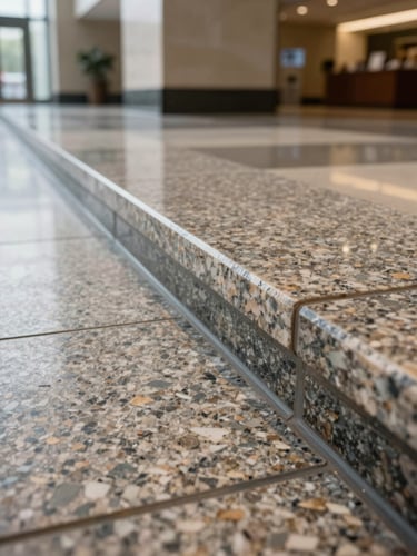 Low-angle detail shot of a granite raised floor panel seam in an institutional lobby, showing the polished stone surface edge and transition joint under north-facing indoor daylight, no people, no showroom aesthetics