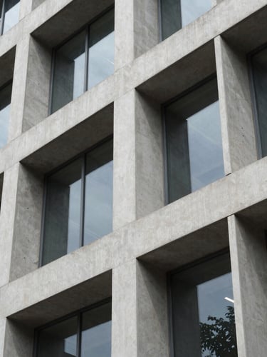 A highly structured modern office facade in Bengaluru, crisp geometric concrete lines, sharp daylight reflection, clean architectural detail.