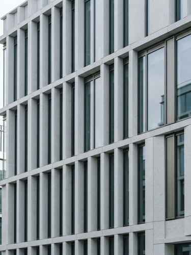 Crisp architectural detail of a modern limestone building facade, sharp geometric lines, bright natural daylight, desaturated cool tones